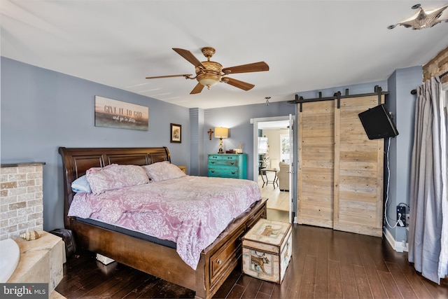 bedroom with ceiling fan, a barn door, and dark hardwood / wood-style floors