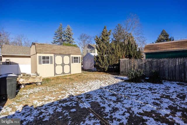 yard layered in snow featuring a storage unit