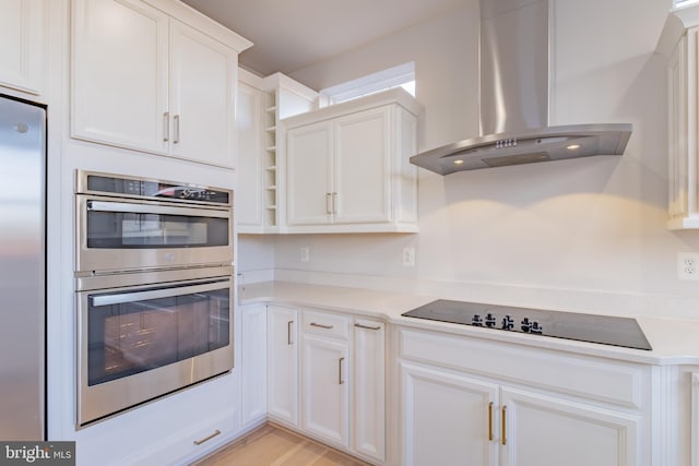 kitchen featuring stainless steel appliances, white cabinetry, wall chimney exhaust hood, and light hardwood / wood-style floors