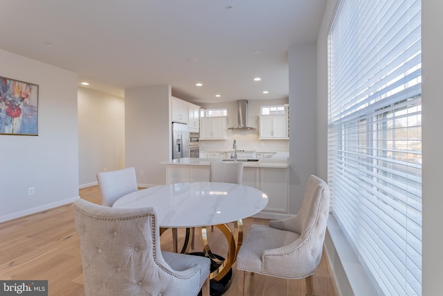 dining area with light wood-type flooring, sink, and a wealth of natural light