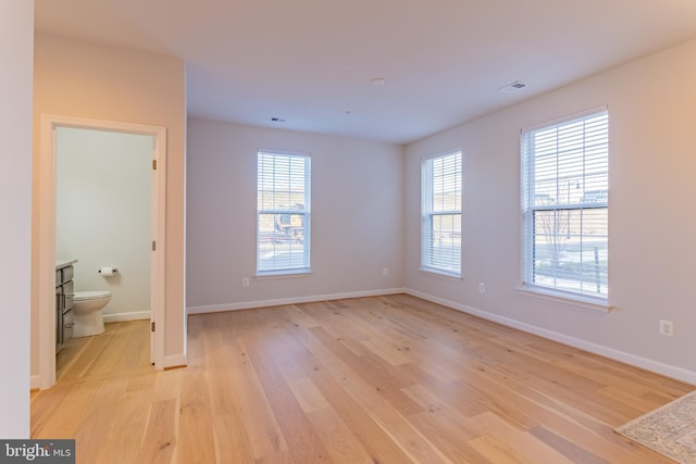 spare room featuring a wealth of natural light and light hardwood / wood-style floors