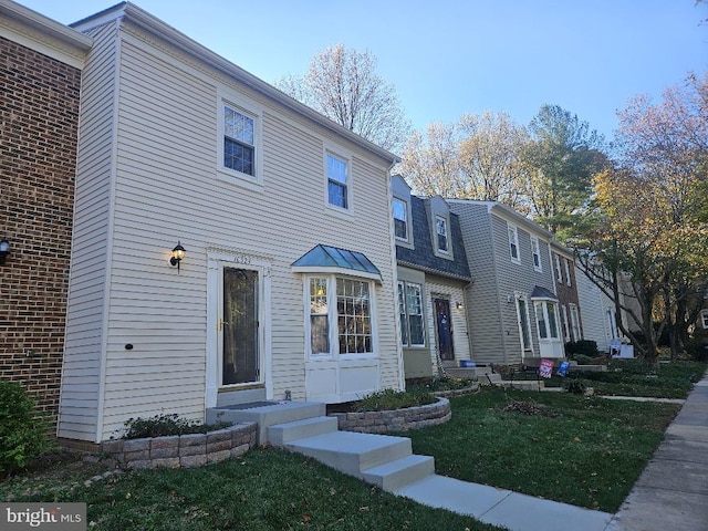 view of front of property with entry steps and a front lawn