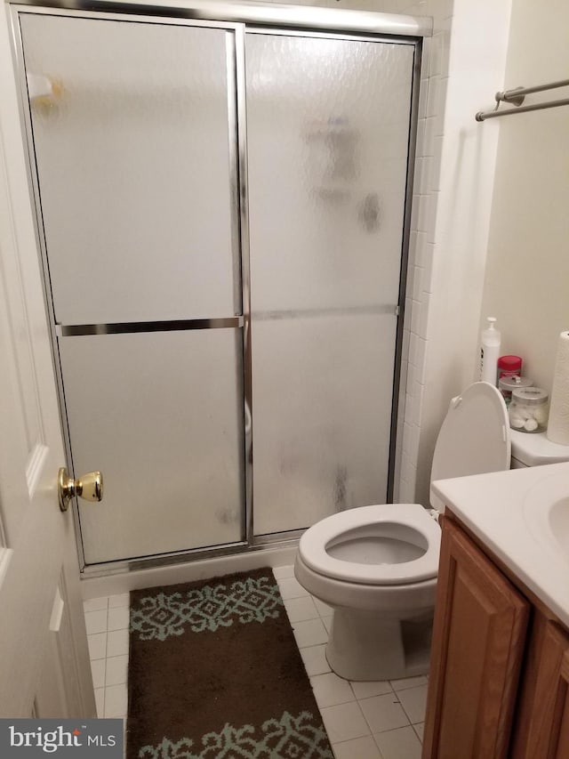 bathroom with tile patterned flooring, vanity, toilet, and a shower with door