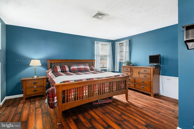 bedroom with a textured ceiling and dark hardwood / wood-style flooring