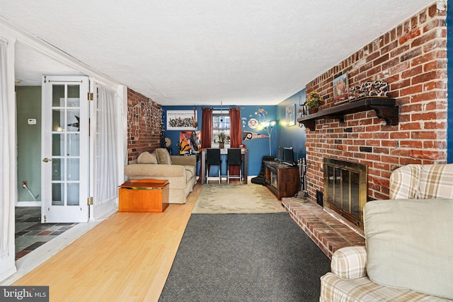 living room featuring wood-type flooring, a fireplace, and a textured ceiling