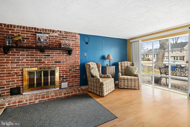 living room with wood-type flooring, a textured ceiling, and a fireplace