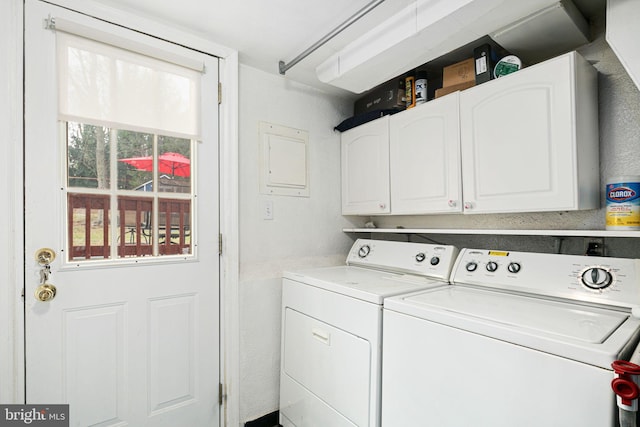 clothes washing area with separate washer and dryer and cabinets