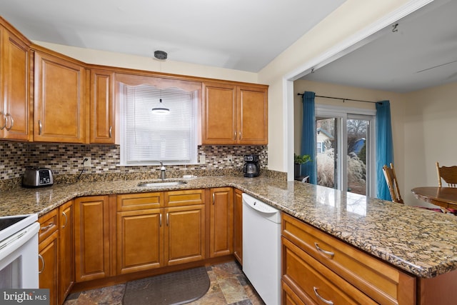 kitchen with white appliances, sink, decorative backsplash, stone countertops, and kitchen peninsula