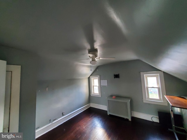 bonus room with ceiling fan, dark hardwood / wood-style flooring, lofted ceiling, and radiator