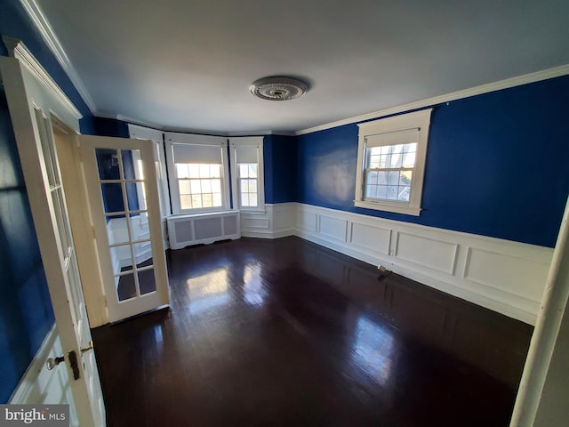 empty room featuring dark hardwood / wood-style flooring, radiator heating unit, and ornamental molding