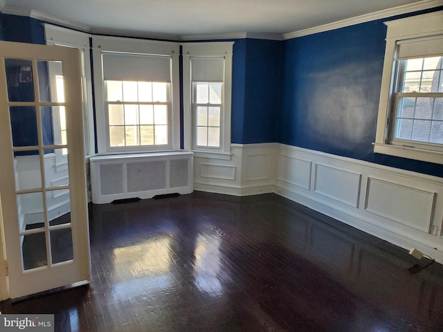 spare room featuring plenty of natural light, dark hardwood / wood-style floors, crown molding, and radiator