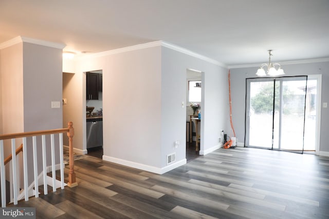 spare room featuring dark hardwood / wood-style flooring, crown molding, and a chandelier