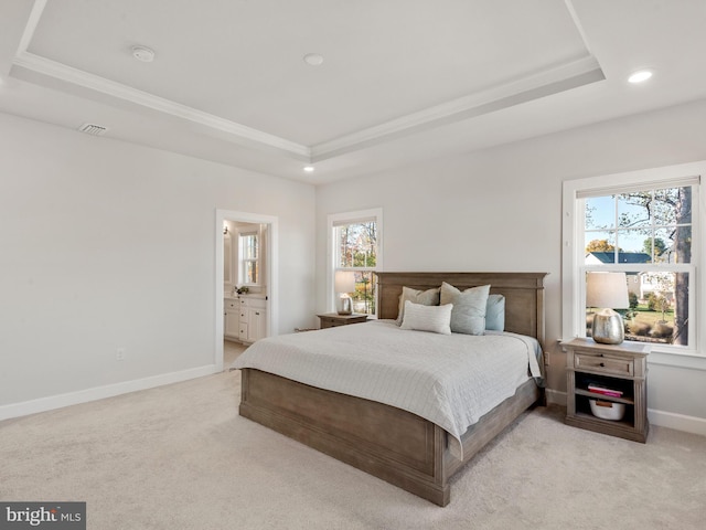 carpeted bedroom with connected bathroom and a raised ceiling