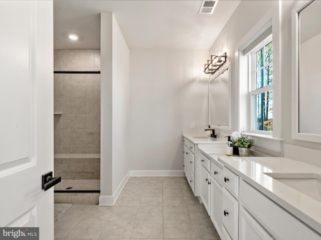 bathroom with tile patterned floors, vanity, and a tile shower