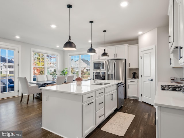 kitchen featuring white cabinetry, sink, stainless steel appliances, an island with sink, and pendant lighting