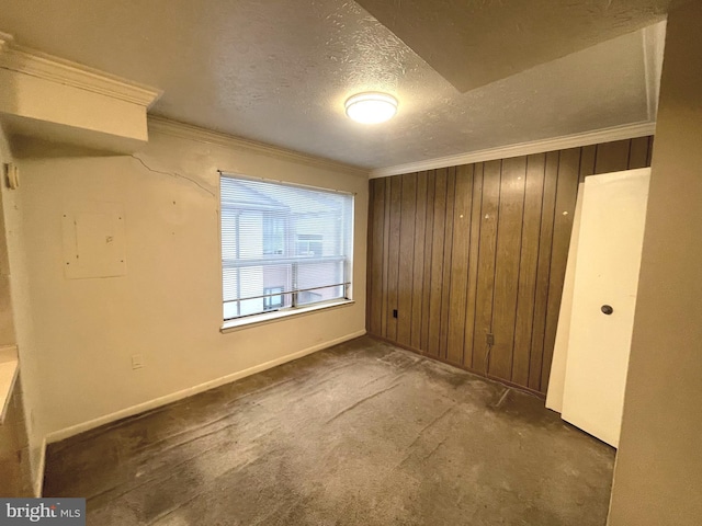 unfurnished bedroom with ornamental molding, a textured ceiling, wooden walls, dark colored carpet, and a closet