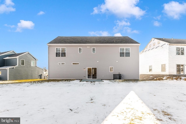 snow covered back of property with central AC