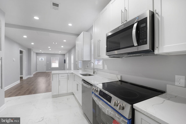 kitchen with white cabinetry, sink, light stone countertops, and appliances with stainless steel finishes