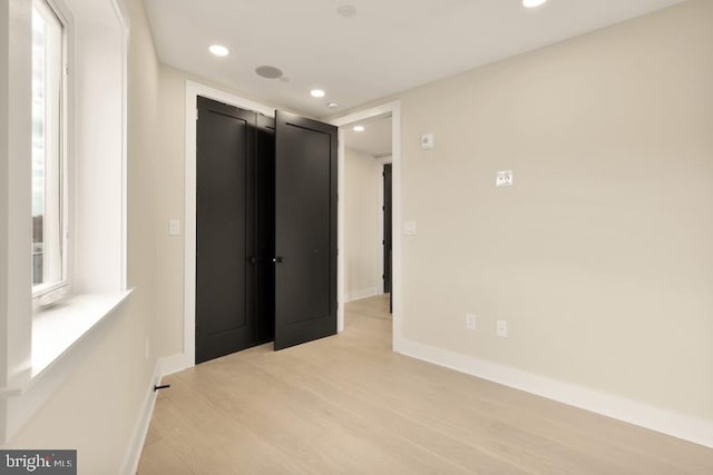 unfurnished bedroom with light wood-type flooring and multiple windows