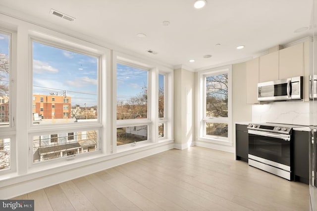 kitchen with white cabinets, crown molding, decorative backsplash, light hardwood / wood-style floors, and stainless steel appliances