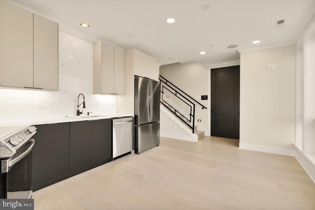 kitchen featuring sink, tasteful backsplash, crown molding, light hardwood / wood-style floors, and appliances with stainless steel finishes