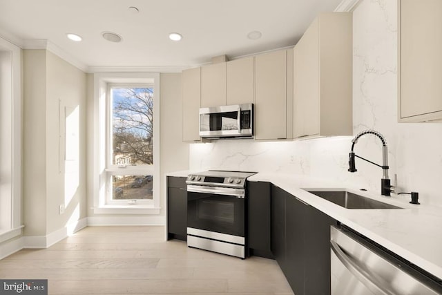 kitchen featuring sink, stainless steel appliances, tasteful backsplash, light hardwood / wood-style flooring, and crown molding