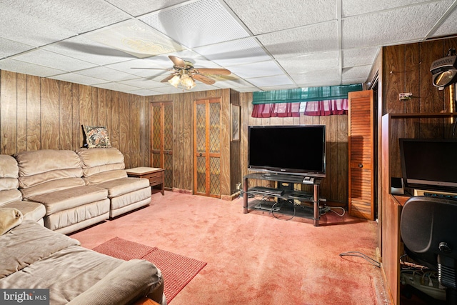 carpeted living room featuring a paneled ceiling, ceiling fan, and wood walls