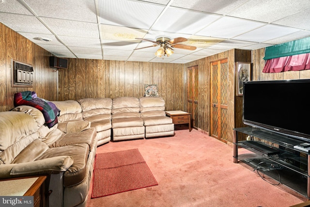 living room featuring a drop ceiling, wood walls, carpet floors, and ceiling fan