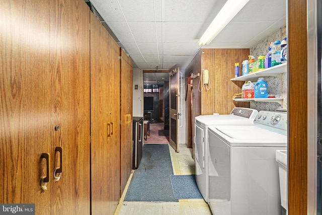 washroom with washing machine and clothes dryer and wood walls