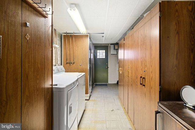 laundry area with cabinets, independent washer and dryer, and wooden walls