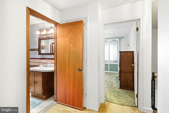 corridor with light carpet and sink