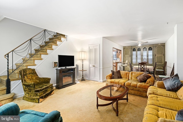 carpeted living room featuring ceiling fan and a fireplace