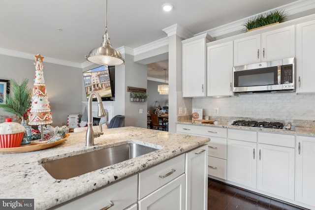 kitchen with pendant lighting, white cabinets, sink, light stone countertops, and appliances with stainless steel finishes