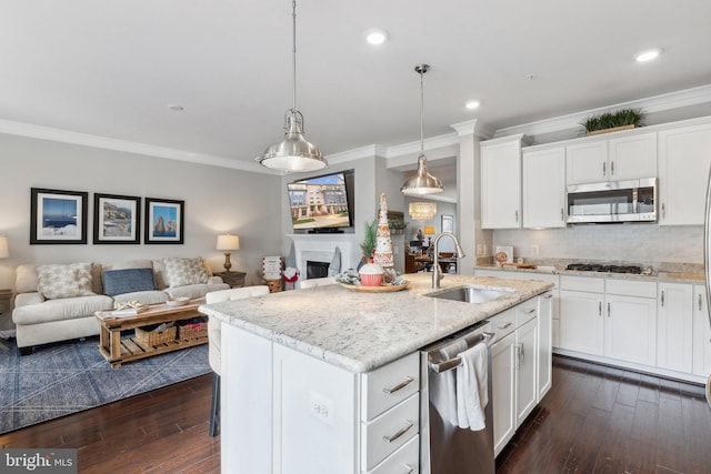 kitchen with appliances with stainless steel finishes, a center island with sink, white cabinetry, and sink