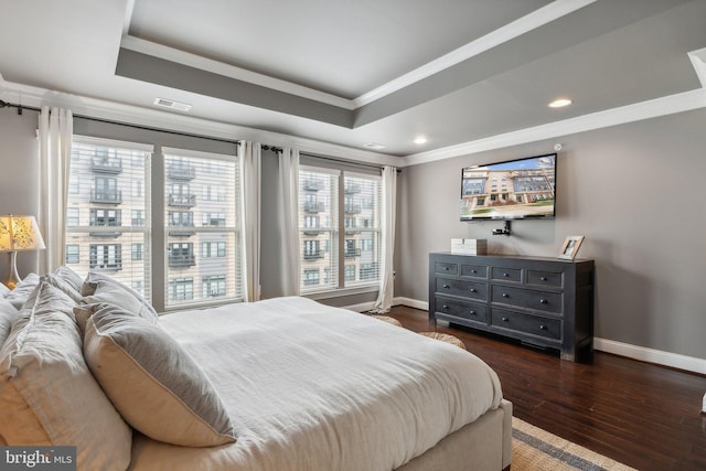 bedroom with a raised ceiling, crown molding, and dark wood-type flooring