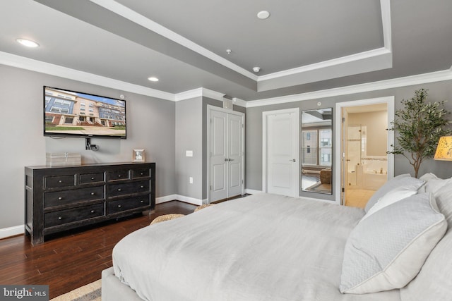 bedroom with dark hardwood / wood-style floors, crown molding, connected bathroom, and a tray ceiling