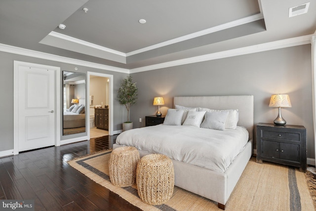 bedroom featuring a raised ceiling, connected bathroom, crown molding, and wood-type flooring