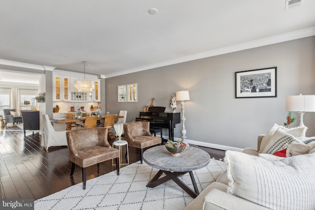 living room with crown molding, wood-type flooring, and an inviting chandelier