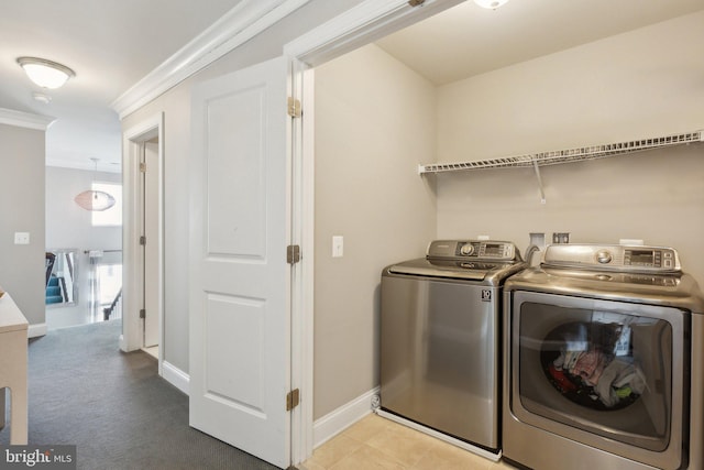 clothes washing area with washing machine and dryer, crown molding, and light colored carpet