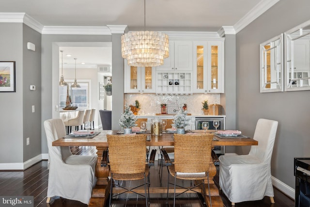 dining space with dark wood-type flooring, a chandelier, and ornamental molding