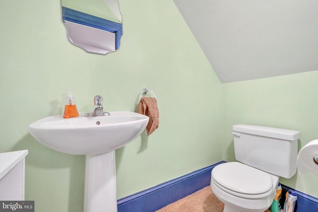 bathroom with toilet, lofted ceiling, and sink