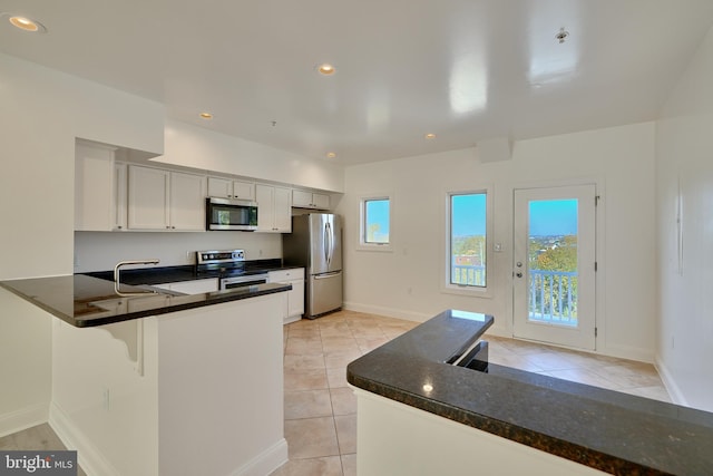 kitchen with kitchen peninsula, white cabinetry, stainless steel appliances, and a wealth of natural light