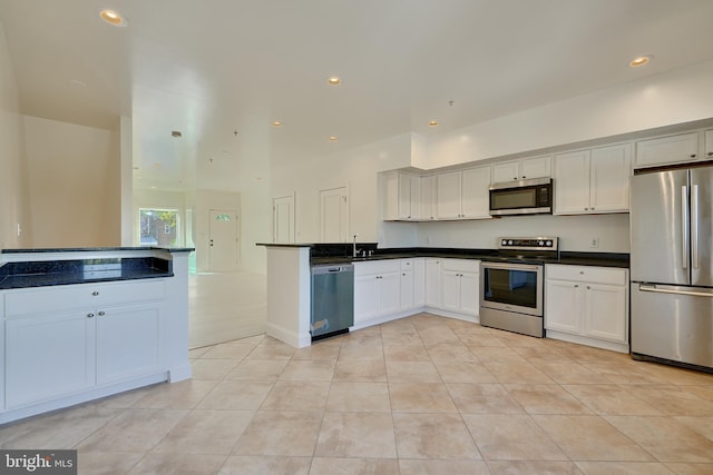 kitchen featuring sink, light tile patterned floors, white cabinetry, kitchen peninsula, and stainless steel appliances