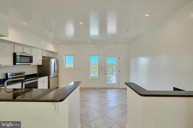 kitchen with stainless steel appliances, white cabinets, kitchen peninsula, a breakfast bar, and light tile patterned flooring