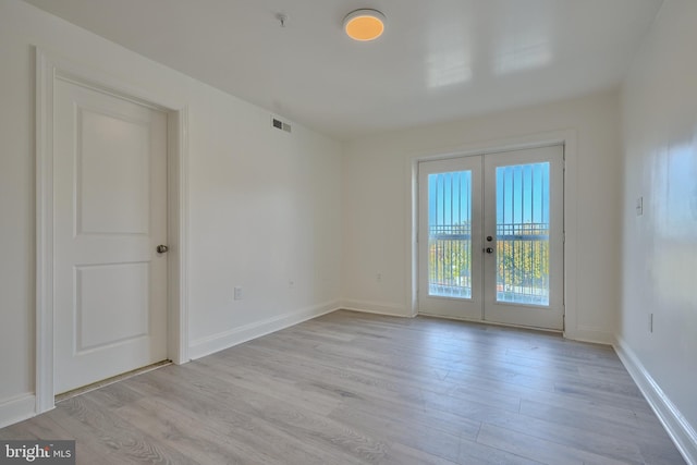 spare room featuring french doors and light wood-type flooring