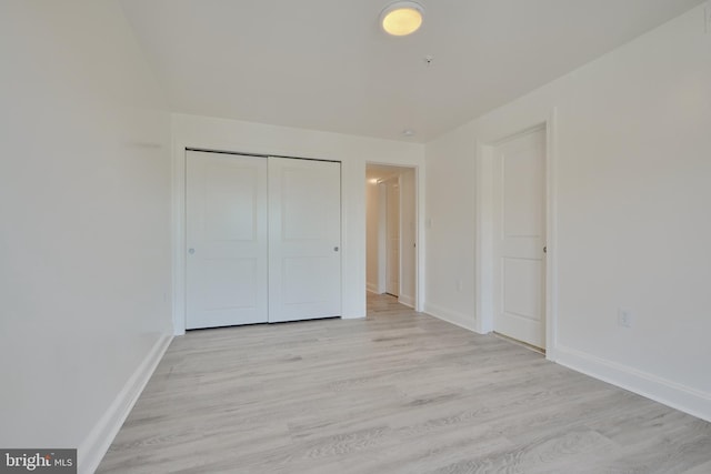 unfurnished bedroom with light wood-type flooring and a closet