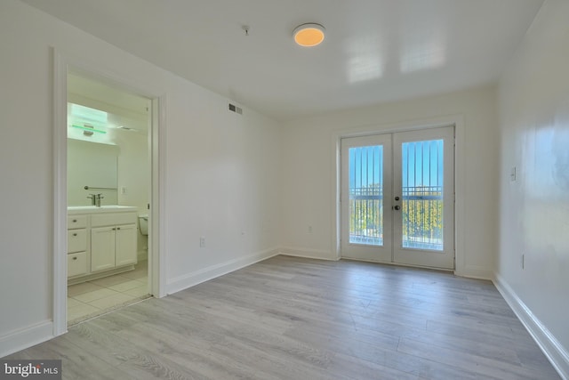 spare room with light wood-type flooring, sink, and french doors