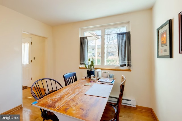 dining space with light hardwood / wood-style flooring and a baseboard heating unit