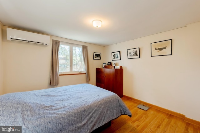 bedroom featuring a wall mounted air conditioner and hardwood / wood-style floors