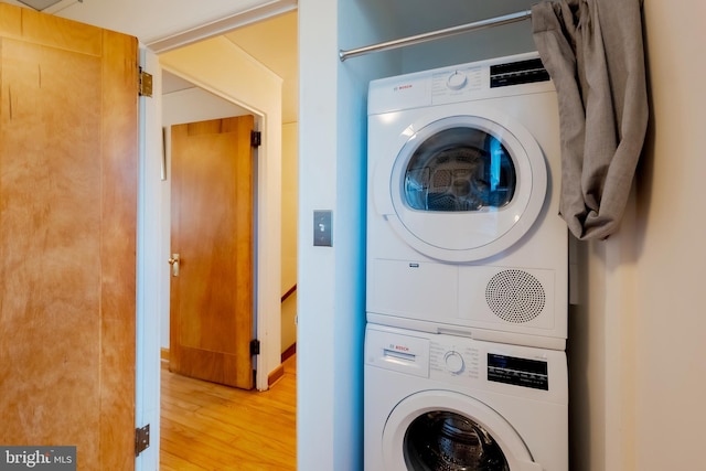 laundry area with stacked washer and clothes dryer and hardwood / wood-style flooring